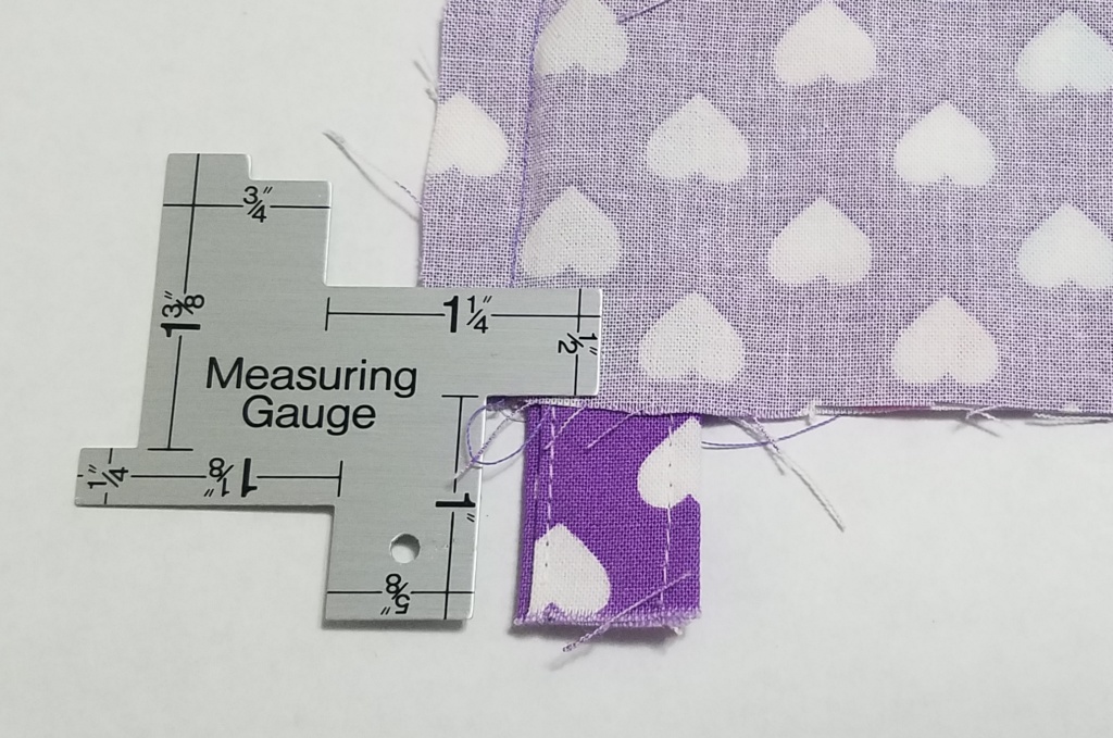 Silver Sewing Measuring Gauge being used on purple fabric with heart