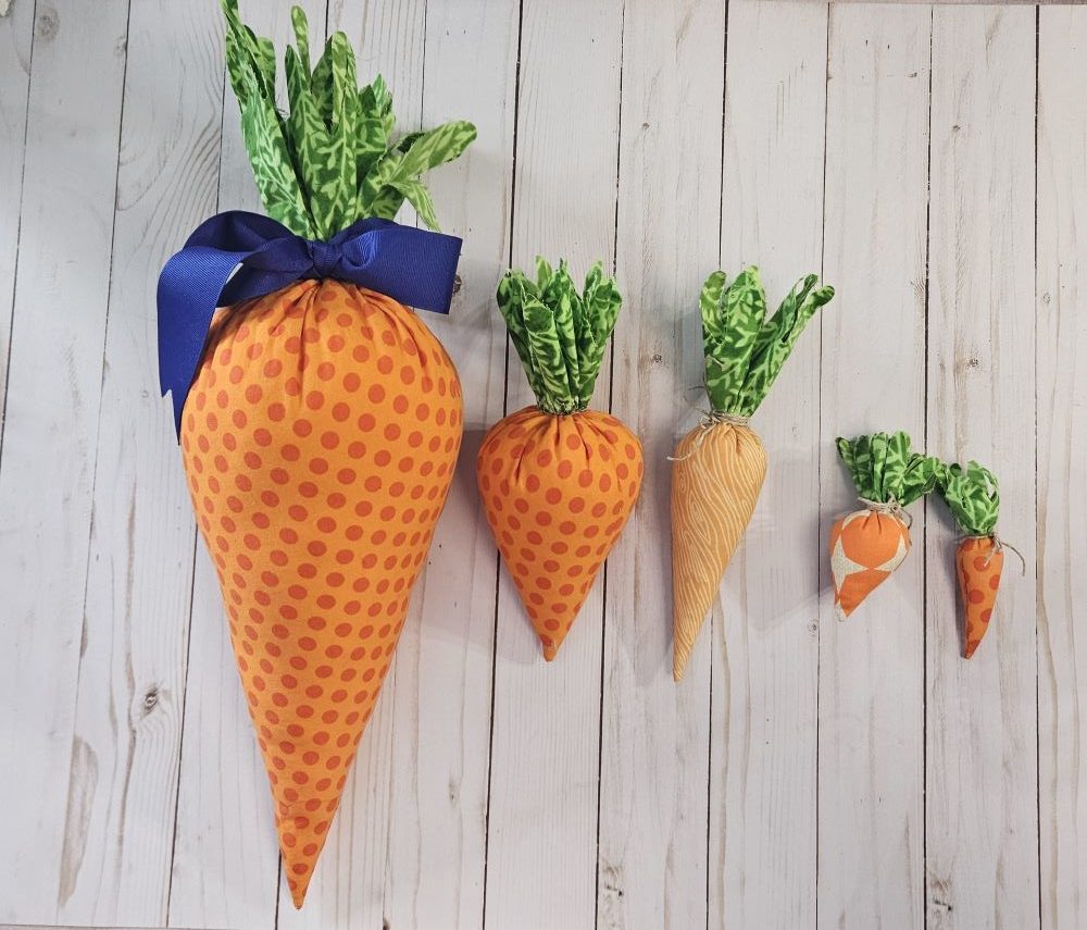 5 orange fabric carrots lined up in size from Jumbo to mini. 