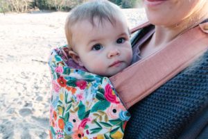 Brightly flowered baby carrier with brown haired child