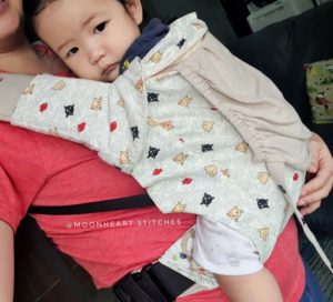 Asian baby in a happy baby carrier with light colored slipcover