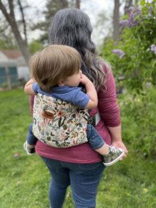 Mom and baby in a happy baby carrier with light flowered slipcover