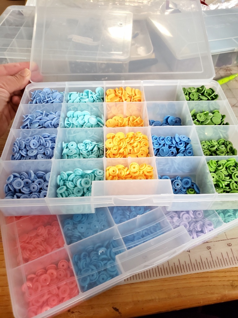 Colorful plastic snaps sorted by color into a plastic container with dividers