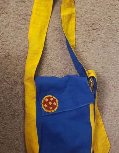 Blue and yellow linen tote bag with nova badge embroidered on the front.