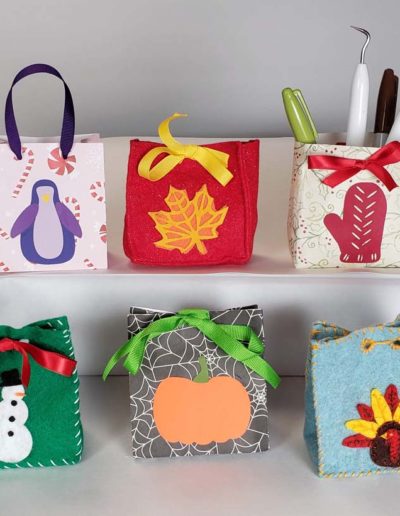 Small gift bags with holiday design element on the front. Penguin, pumpkin, turkey, mitten, snowman, leaf