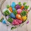 white wicker Easter basket filled with pastel plastic eggs and rainbow colored fabric carrots.