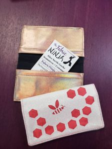two bee themed mini wallets for business cards. One is white glitter canvas with pink and the other is black and holographic faux leather