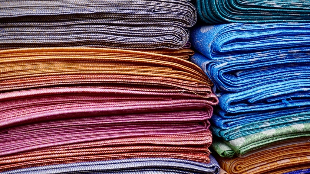 piles of fabric in pinks, orange, grey and blue