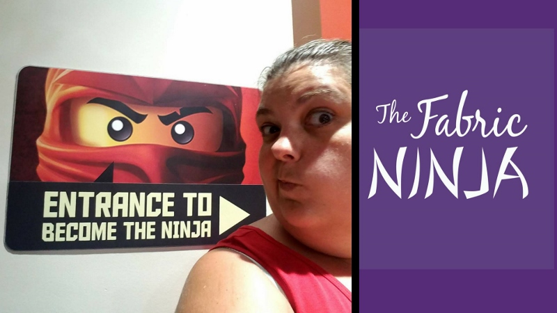 Entrance to become to the ninja sign with lego ninjago character on it with yellow face and red head wrap. Alice in making a silly face next to the sign. 