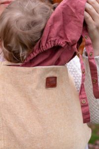 Cream linen slipcover on pink onbuhimo with sleeping hood coming out of zippered opening