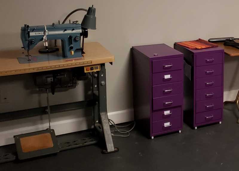 2 sets of purple drawers next to a sewing machine. 
