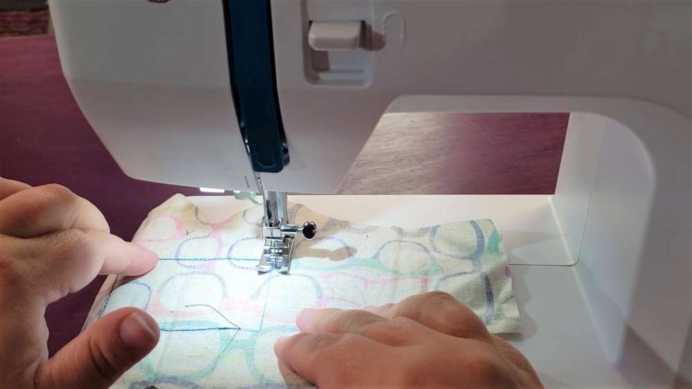 Sewing machine stitching out a rectangle on tan fabric