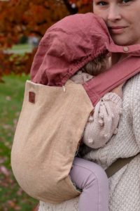 baby sleeping under pink hood of onbuhimo carrier with cream slipcover