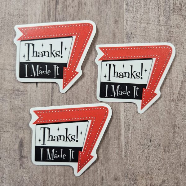 three stickers say, "Thanks! I Made It" in a 1960 sign style with arrow around one edge pointing down. Arrow is red and the sign is black and white with black writing