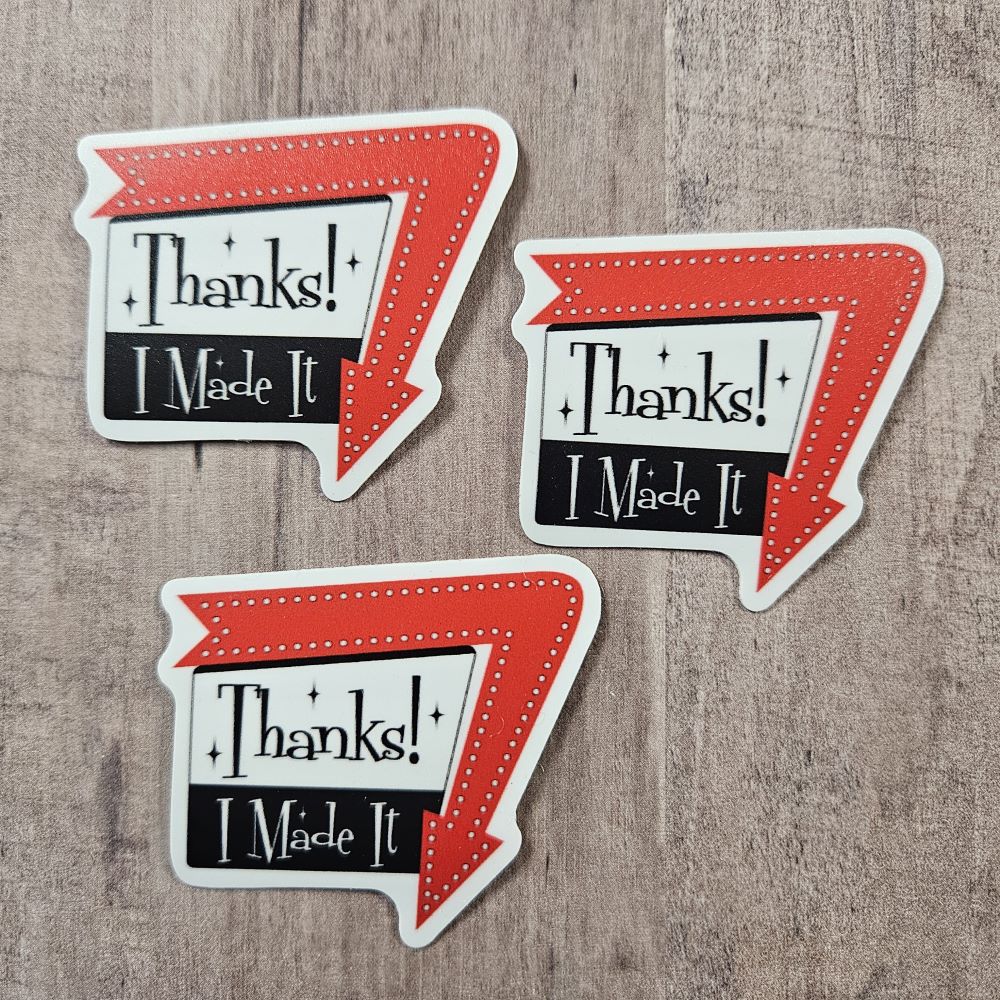three stickers say, "Thanks! I Made It" in a 1960 sign style with arrow around one edge pointing down. Arrow is red and the sign is black and white with black writing