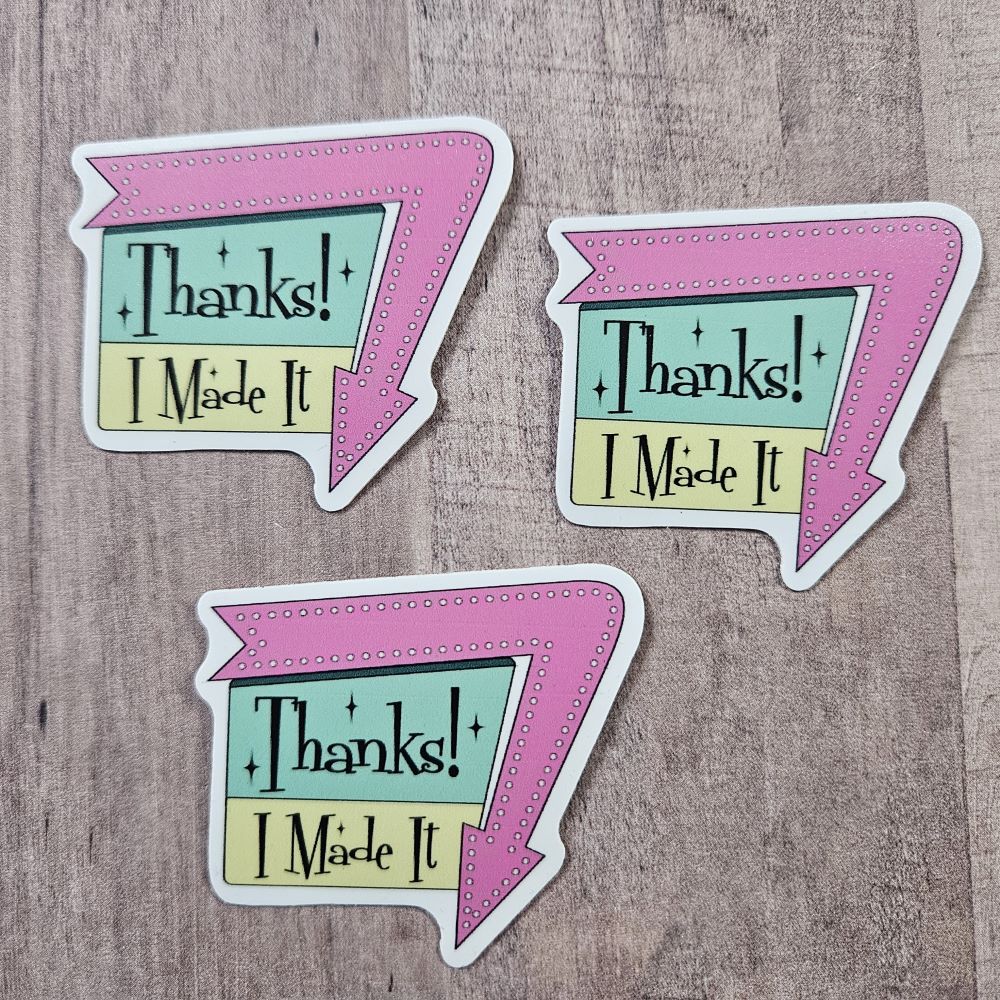 three stickers say, "Thanks! I Made It" in a 1960 sign style with arrow around one edge pointing down. Arrow is pink and the sign is Aqua and a yellow green with black writing
