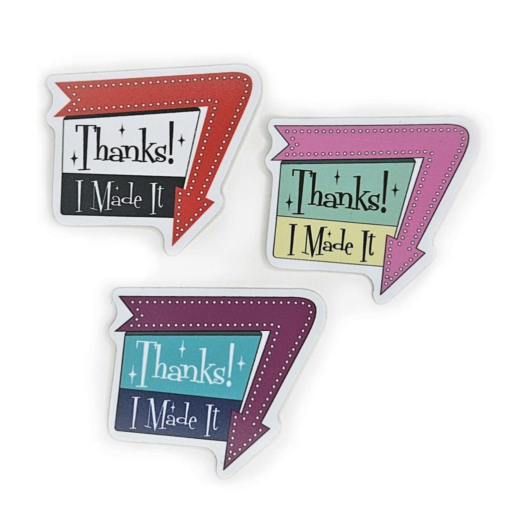 three stickers say, "Thanks! I Made It" in a 1960 sign style with arrow around one edge pointing down. each in a different color inspired by 1960
