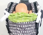 green sleeping hood with white ties scrunched down behind the babys neck