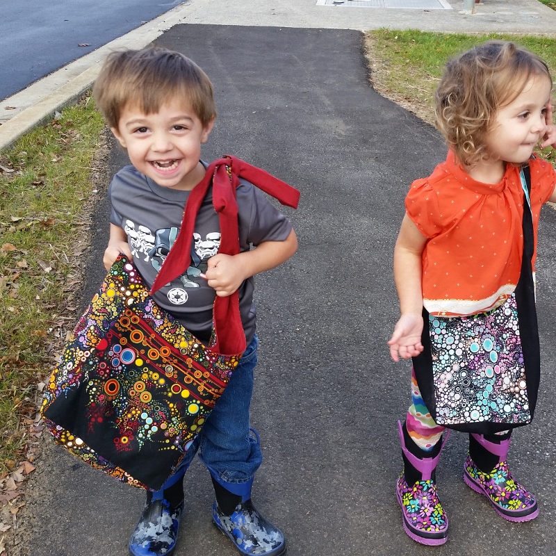 two happy children wearing colorful tote bags